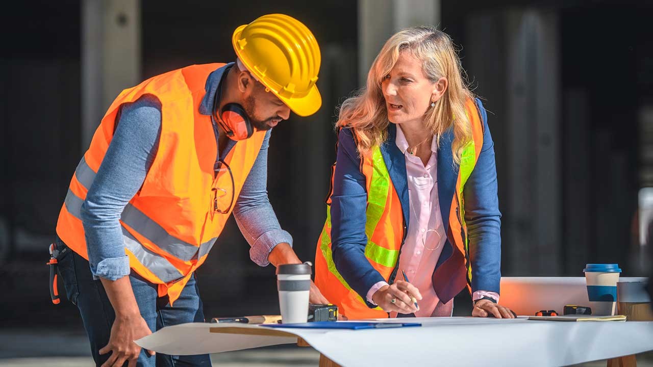 Construction site coordinator standing at a planning table with foreman.