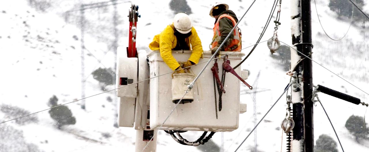 Two workers in bucket truck doing construction work on power lines.