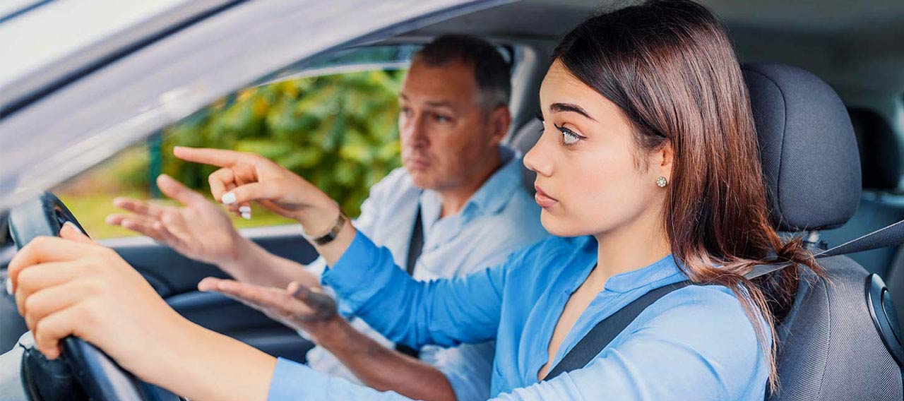 woman taking driving lessons from instructor